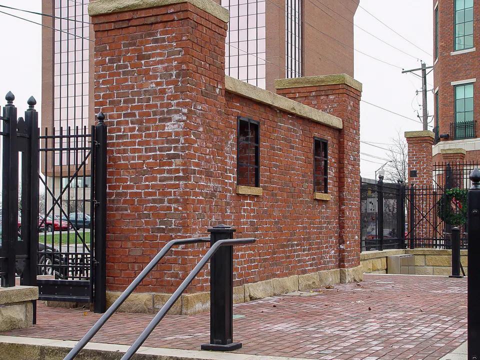 Brick and stone entry pier with iron gate, handrail, and brick paving at Brewer's Yard.